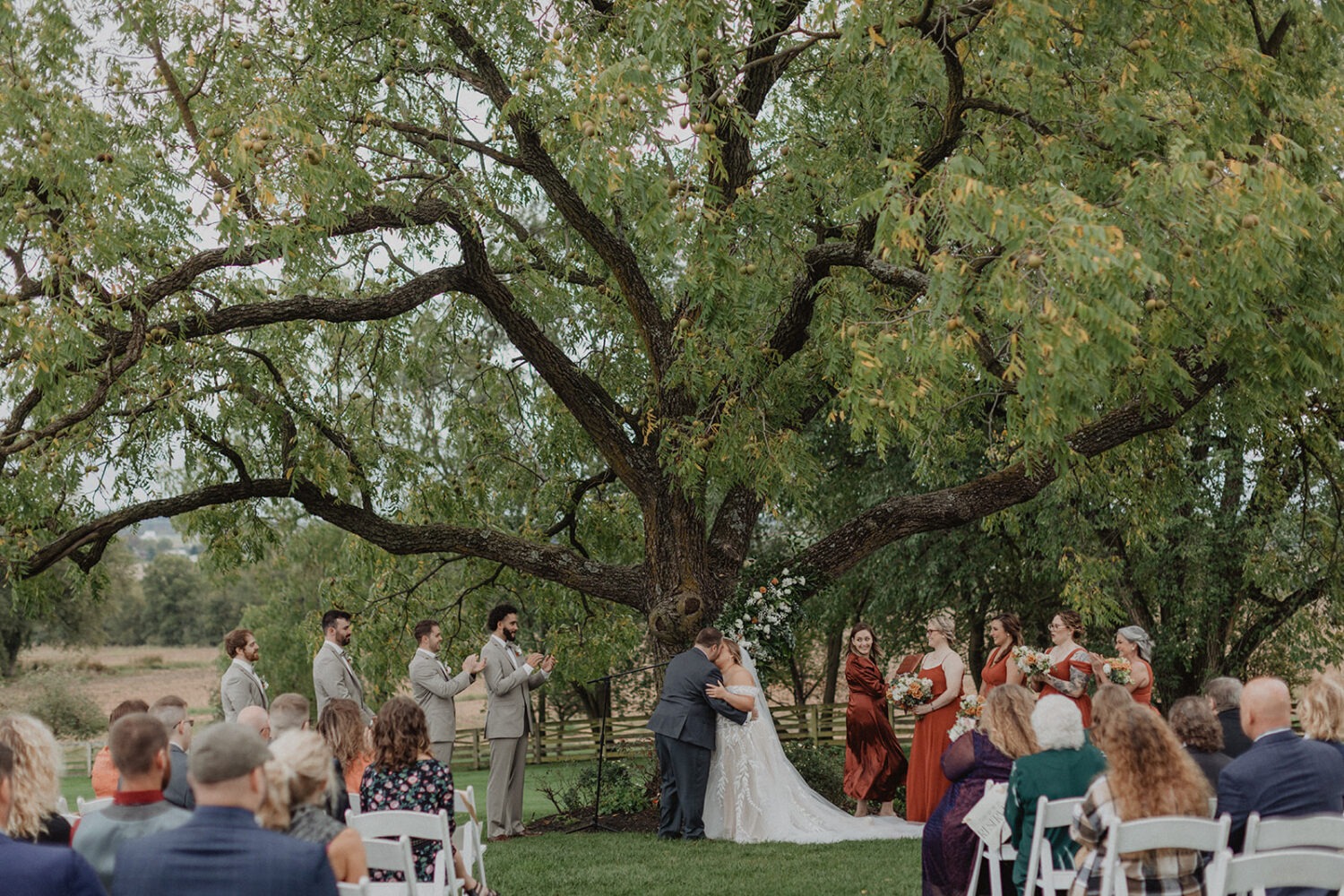 couple kisses under tree at outdoor Walker's Overlook farm wedding venue
 