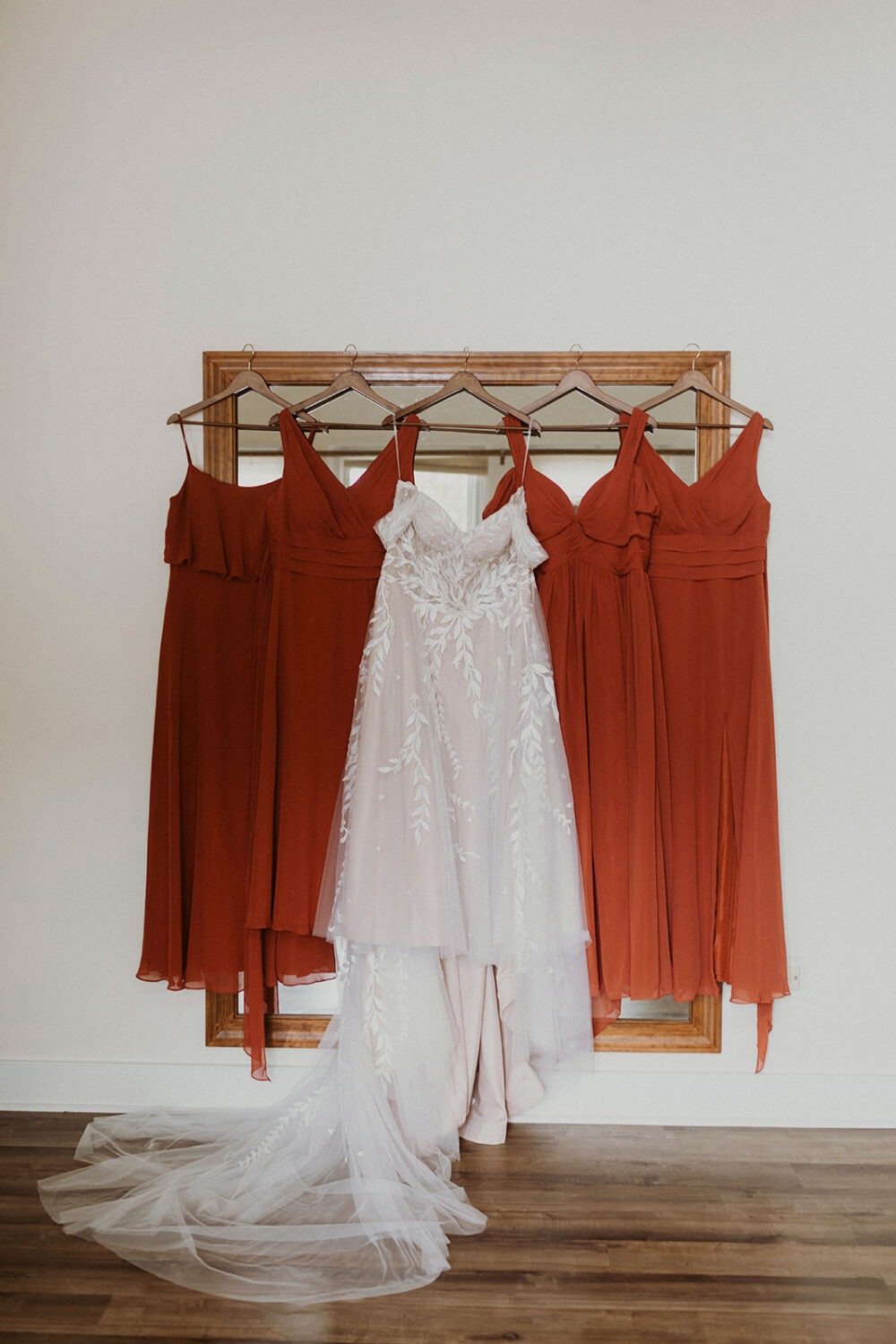 burnt orange bridesmaid dresses beside white wedding dress