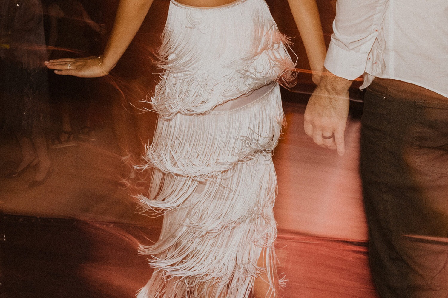 bride wears white beaded fringe dress as example of 2024 wedding trends