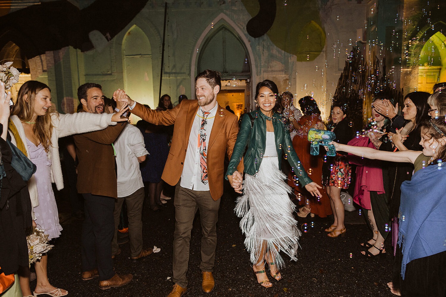 couple exits under bubbles as example of 2024 wedding trends