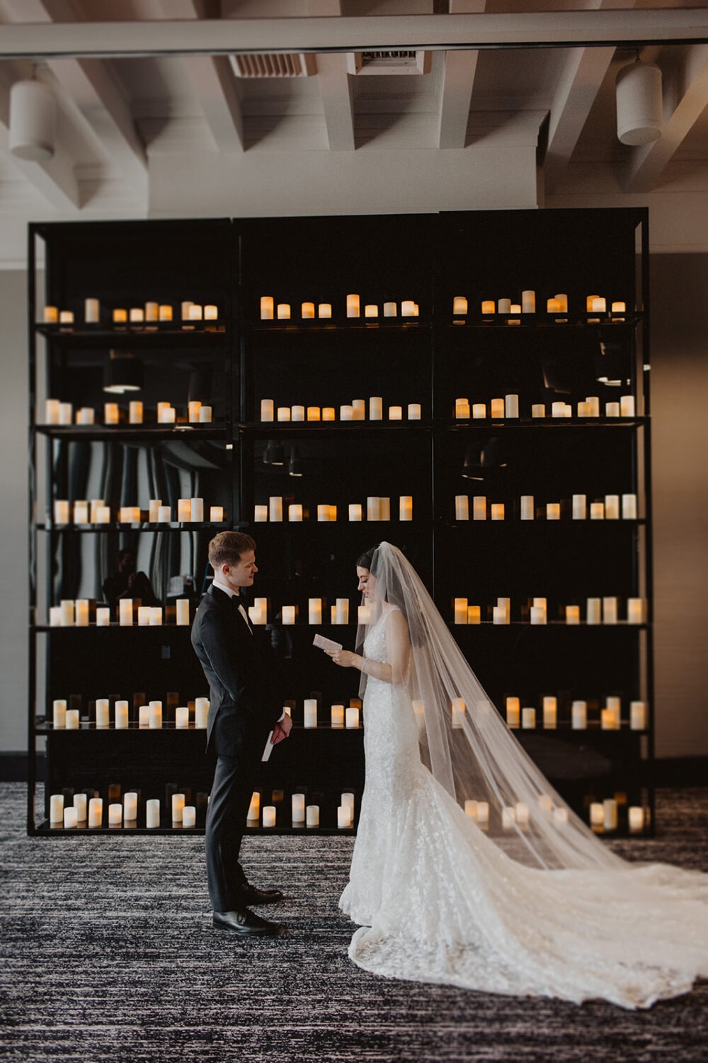 couple exchanges private vows in front of candle wall as example of 2024 wedding trends