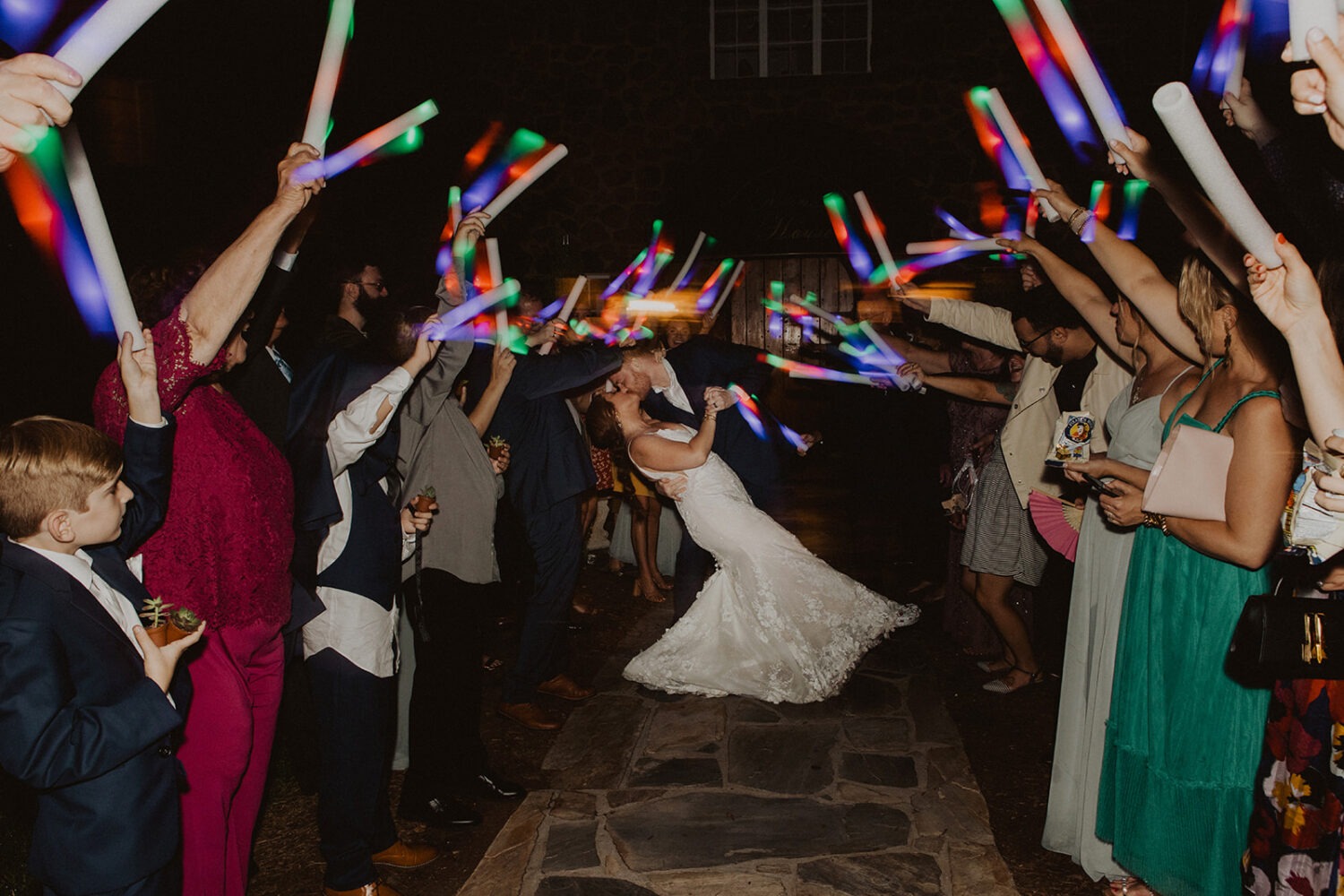 couple exits under fiber optic wands as example of 2024 wedding trends