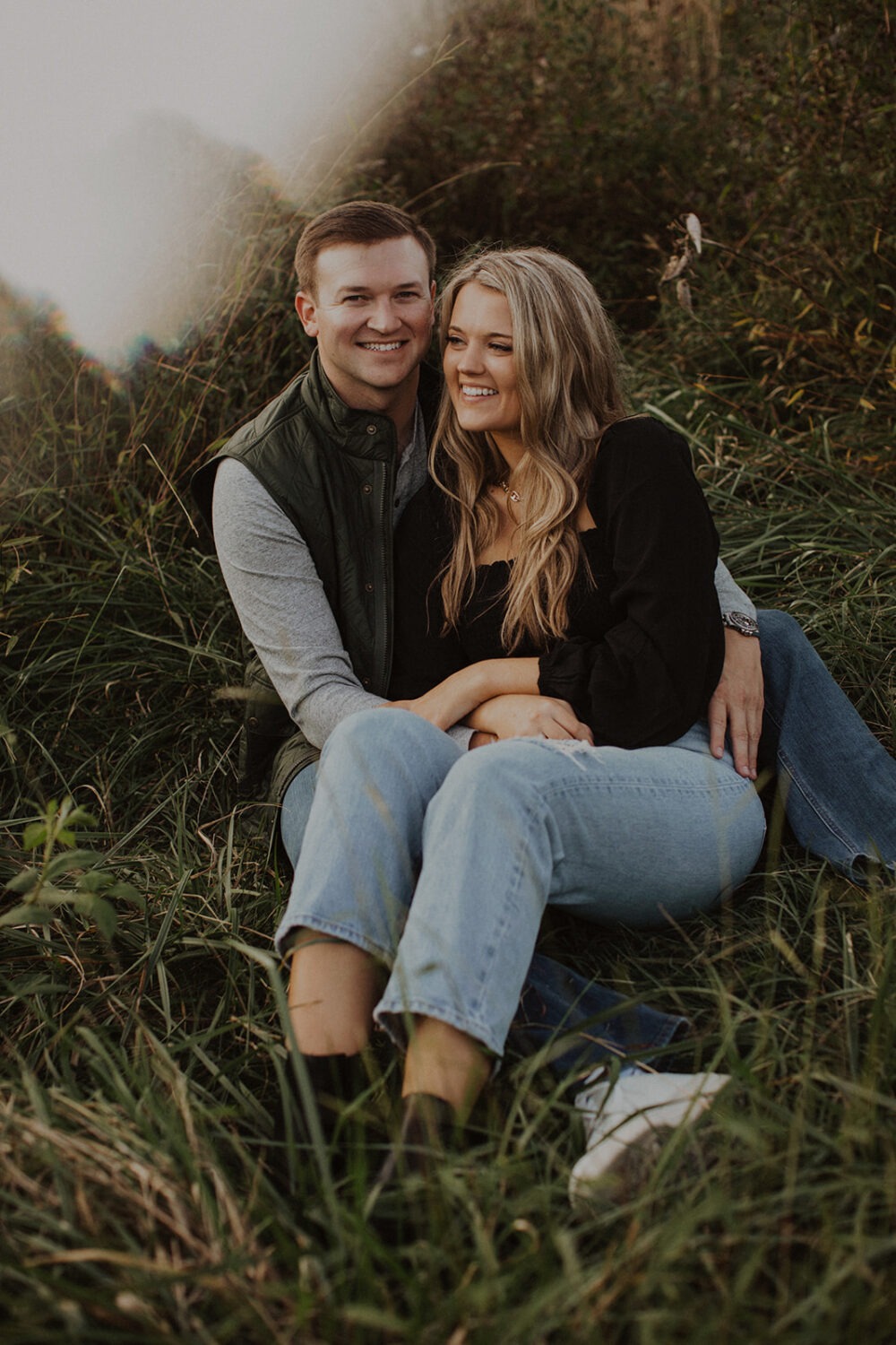 couple sits in grass at outdoor park engagement session