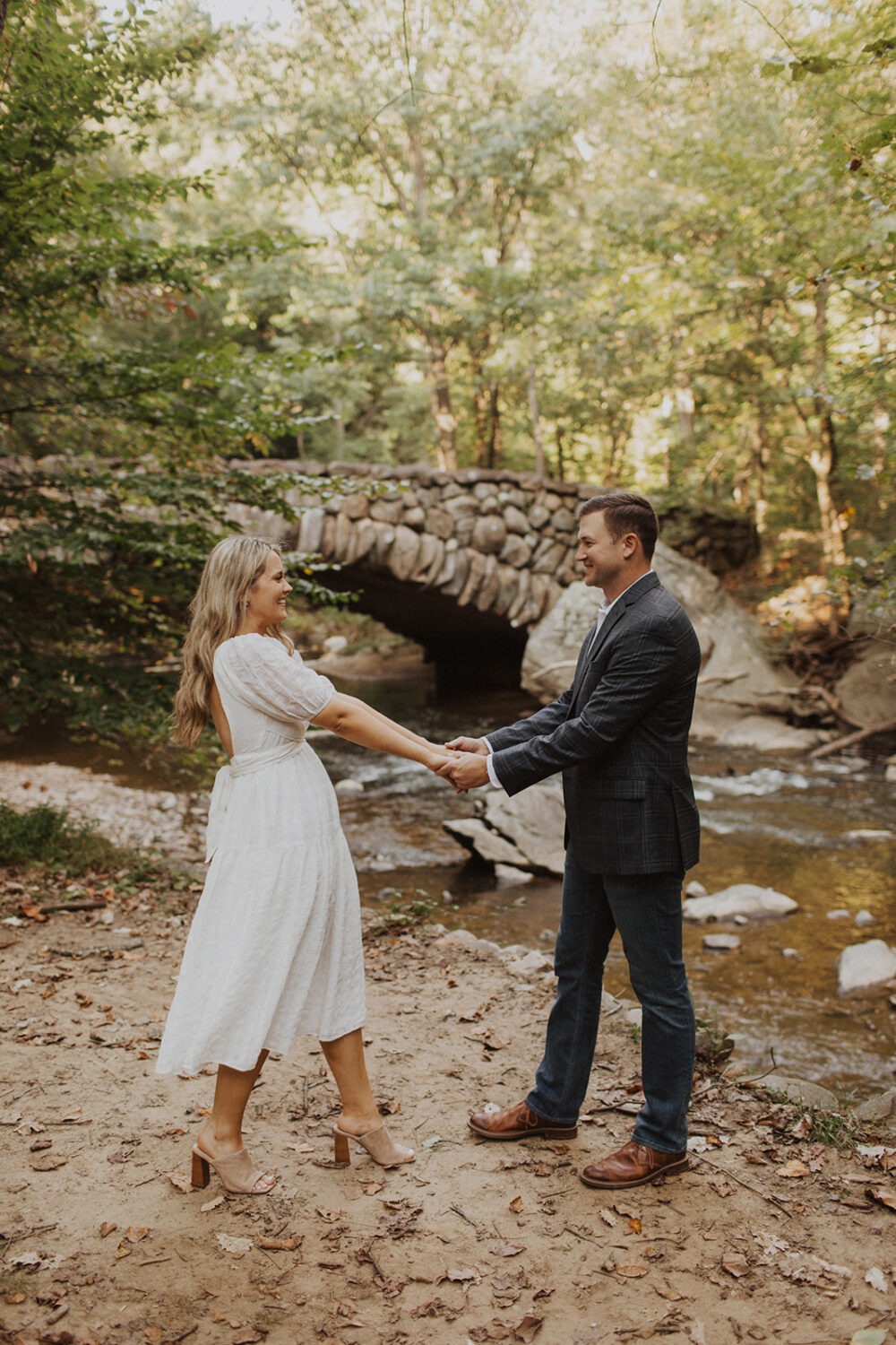 couple twirls beside bridge for Rock Creek Park photos