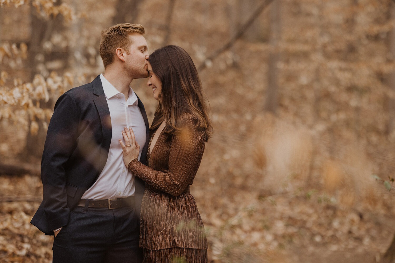 couple kisses at fall forest engagement sesssion