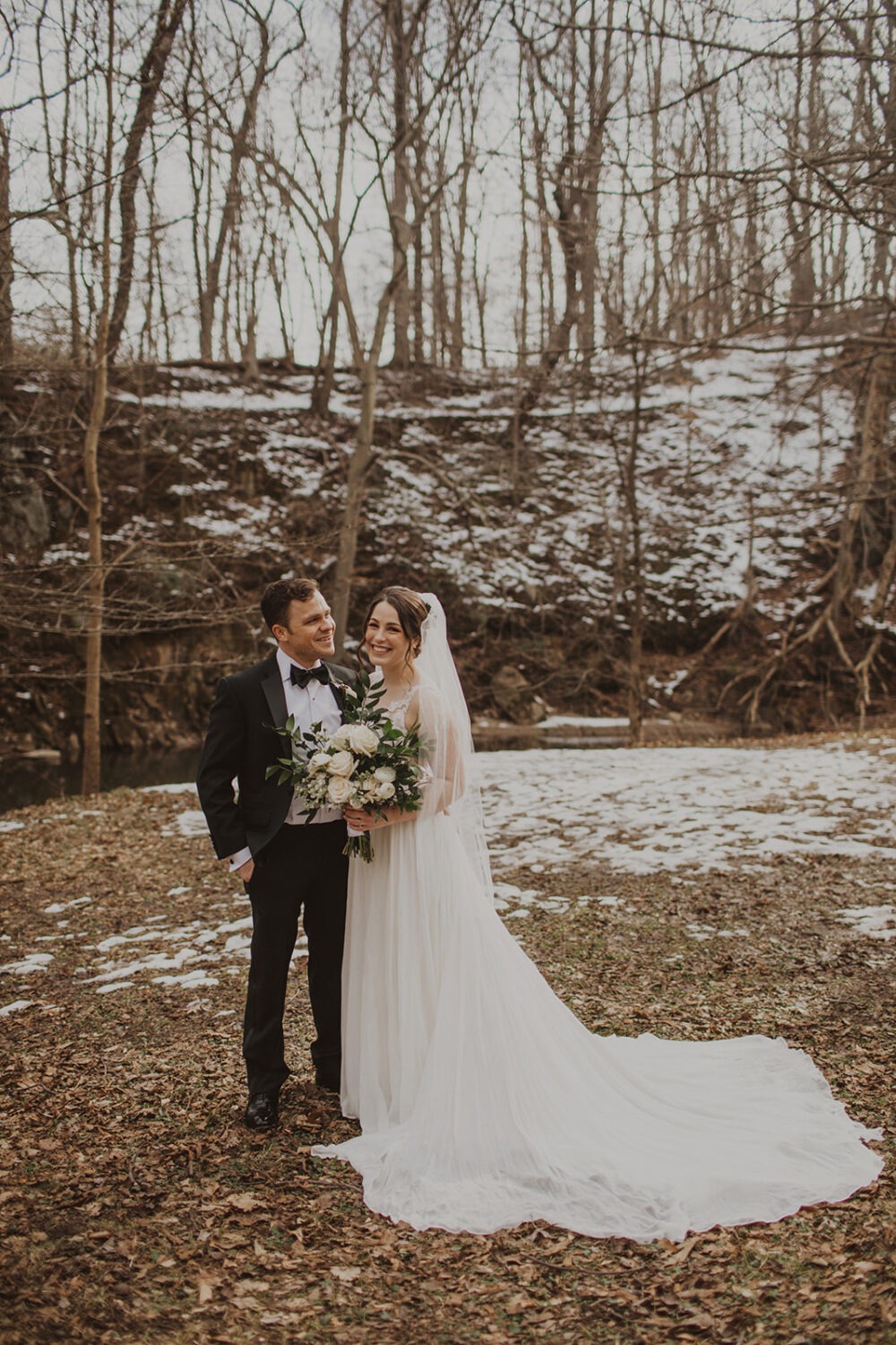 couple embraces at snow-covered forest elopement