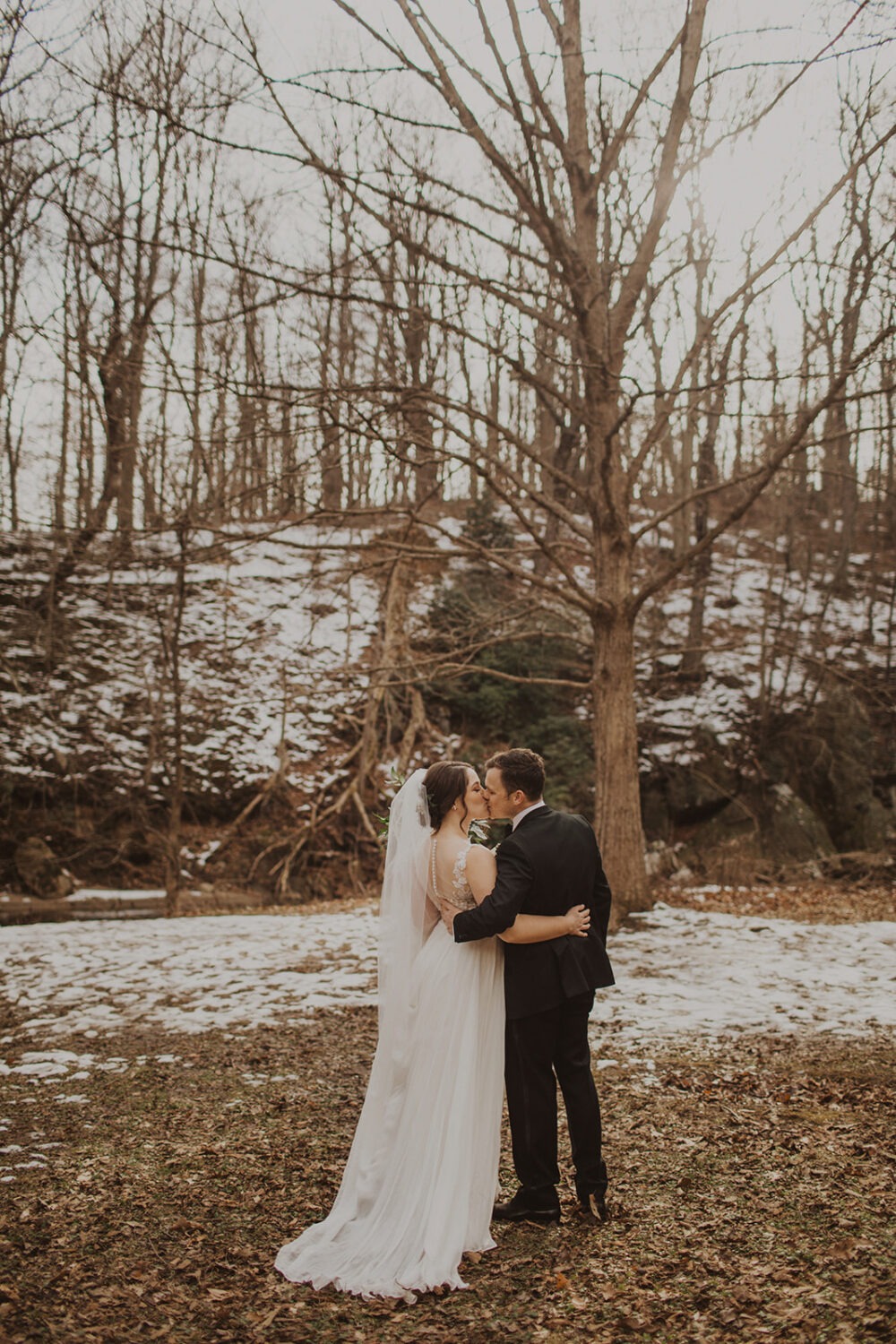 couple kisses at snow-covered forest elopement