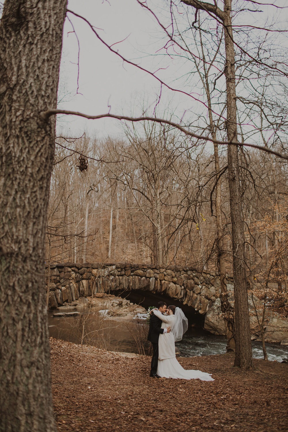 couple kisses by bridge for Rock Creek Park photos