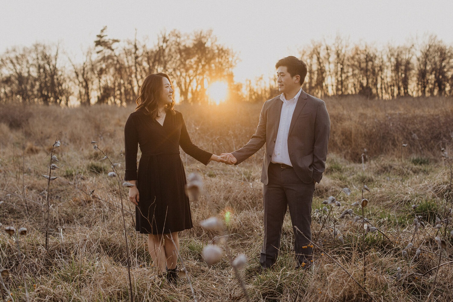 couple holds hands in sunset field