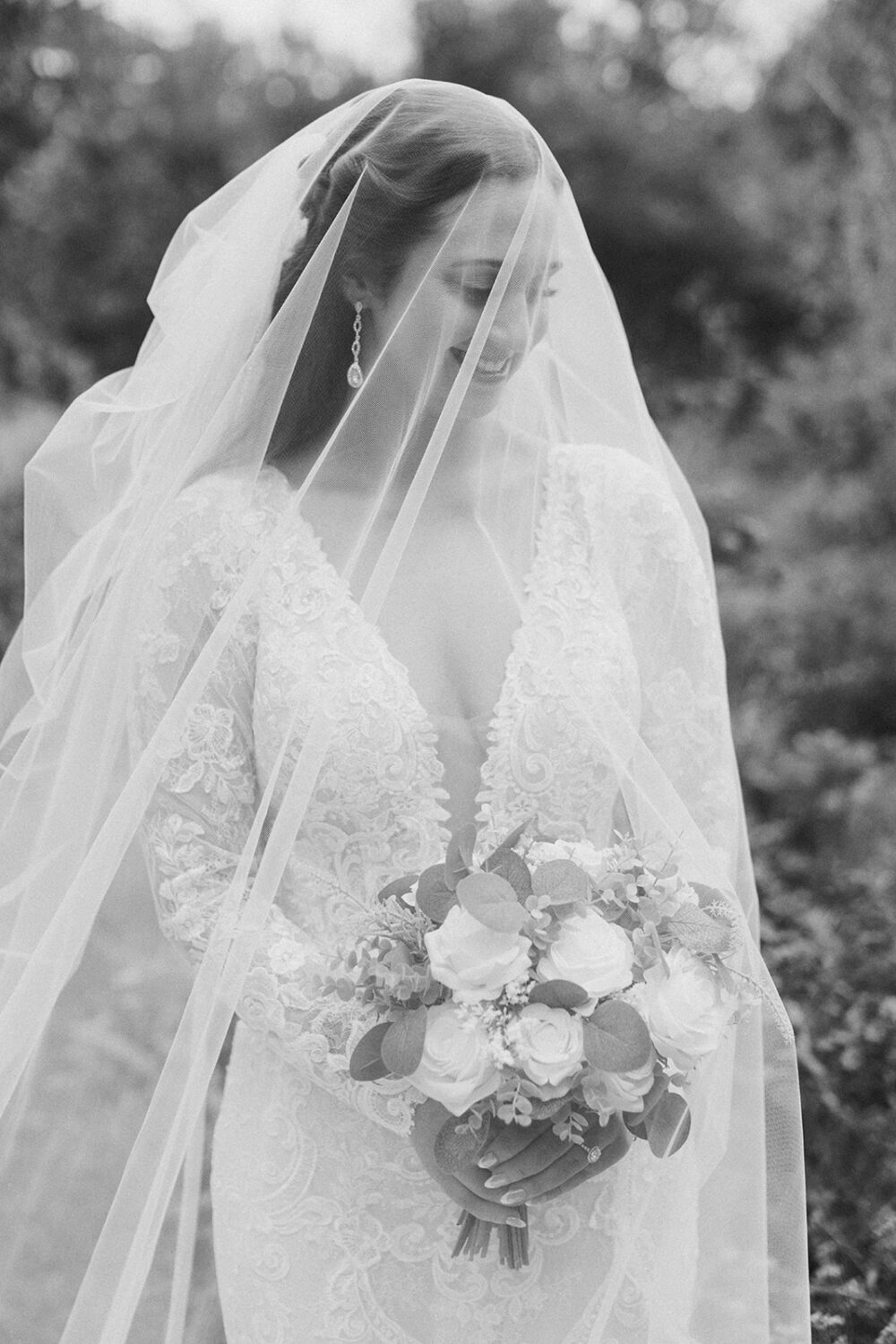 bride holds white rose wedding bouquet under wedding veil 