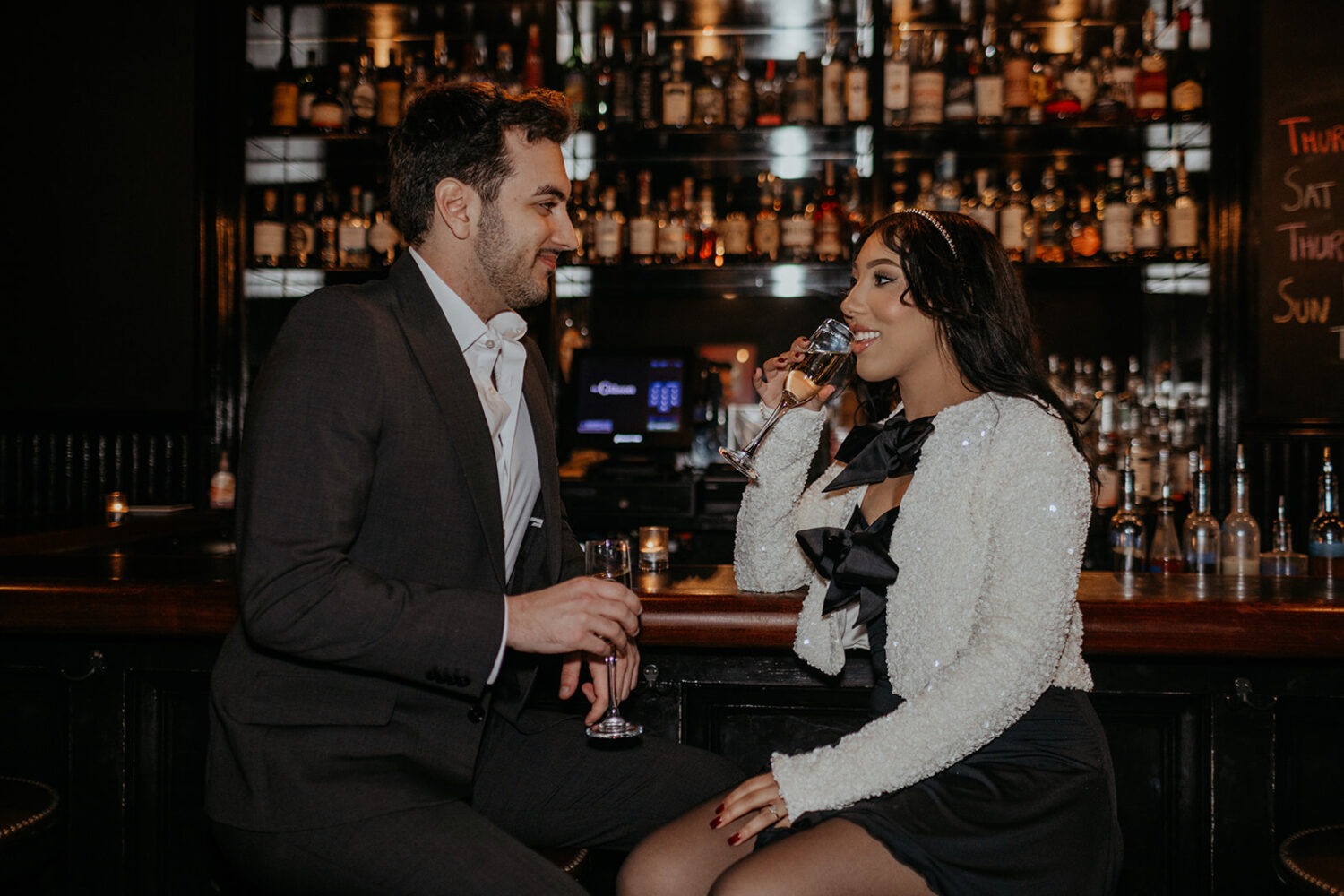 couple drinks champagne at bar during engagement session 
