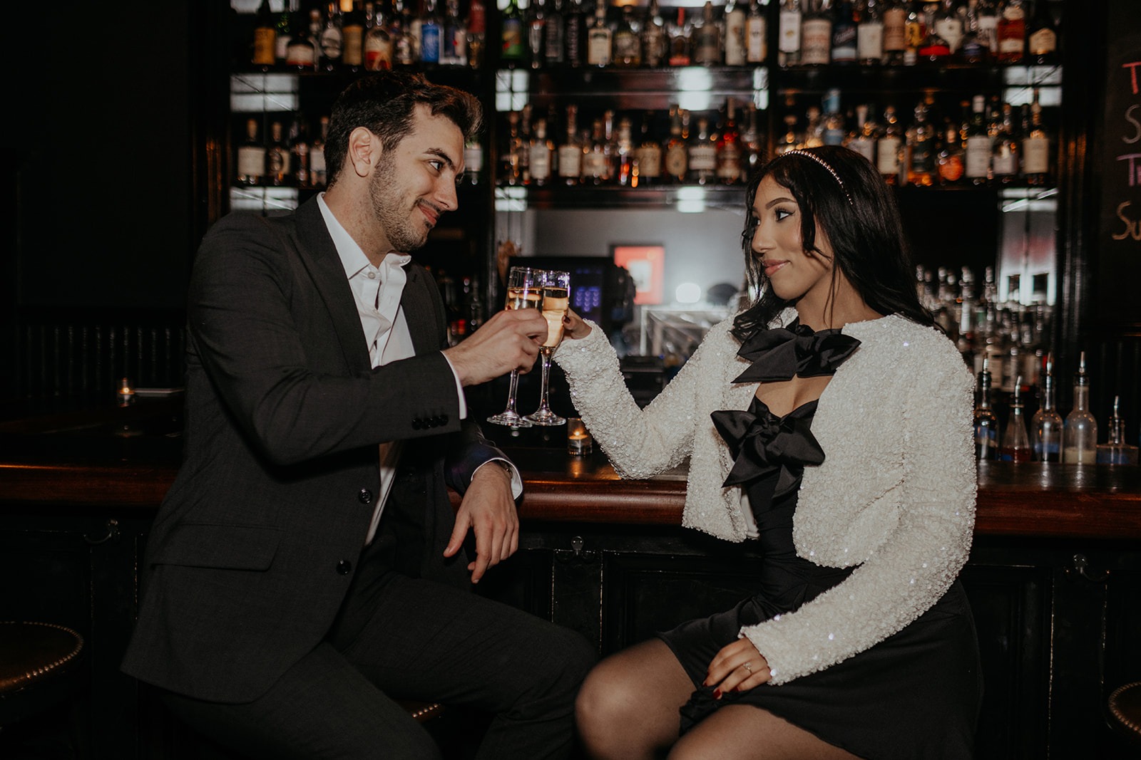 couple cheers at cocktail bar engagement session