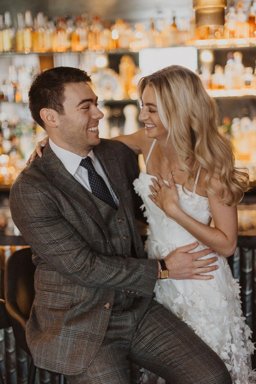 couple laughs embracing at bar engagement session 