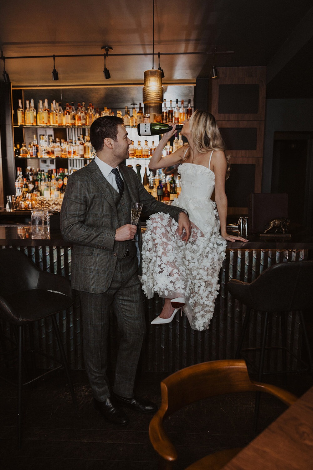 bride sits on bar with groom at engagement session 