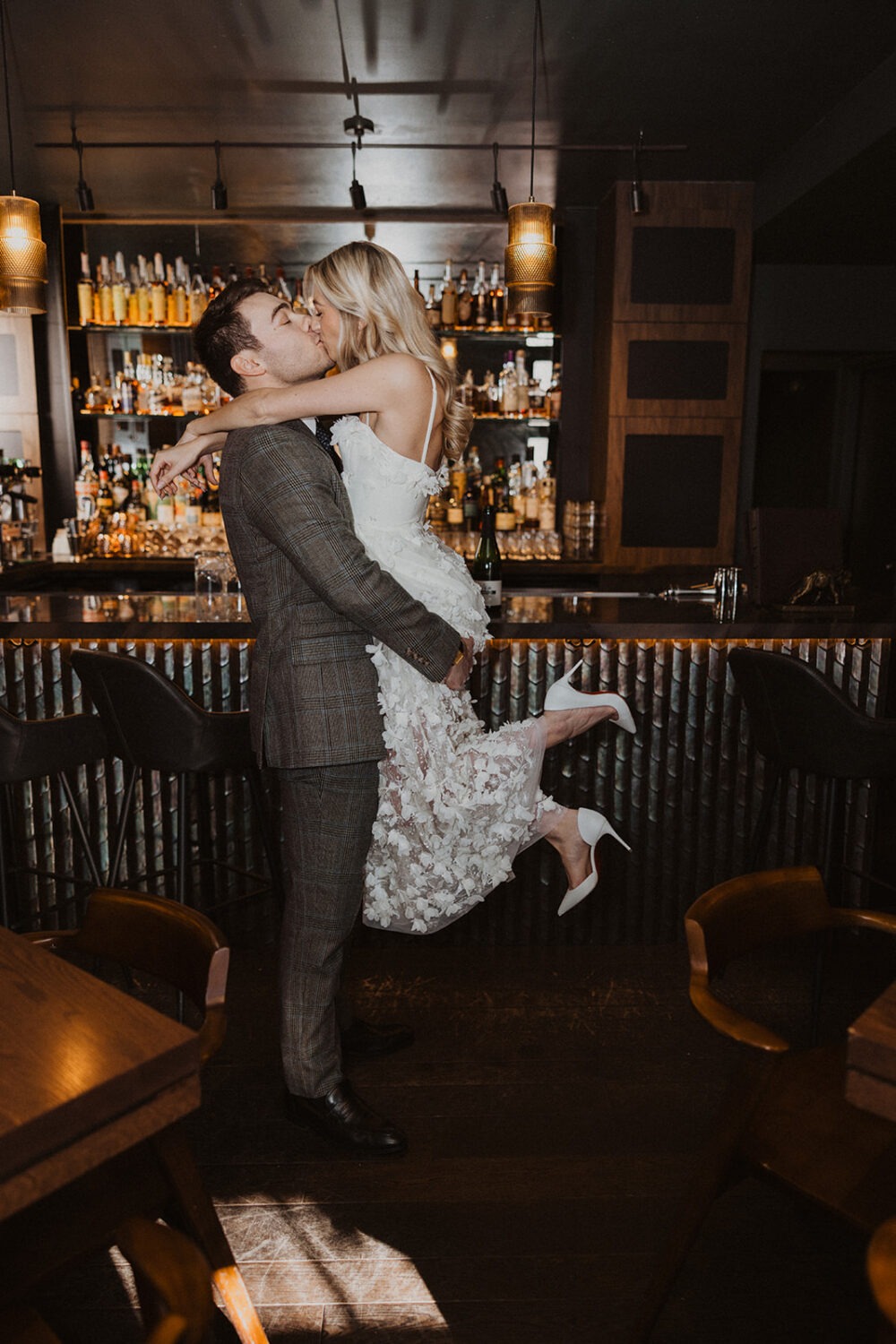 couple kisses in front of bar at speakeasy engagement session 