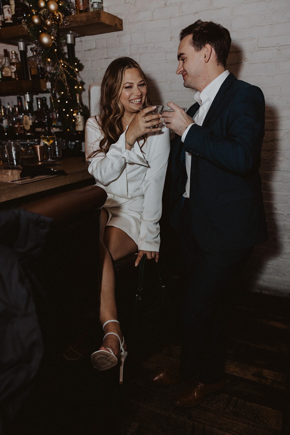couple cheers cocktails at bar engagement session 