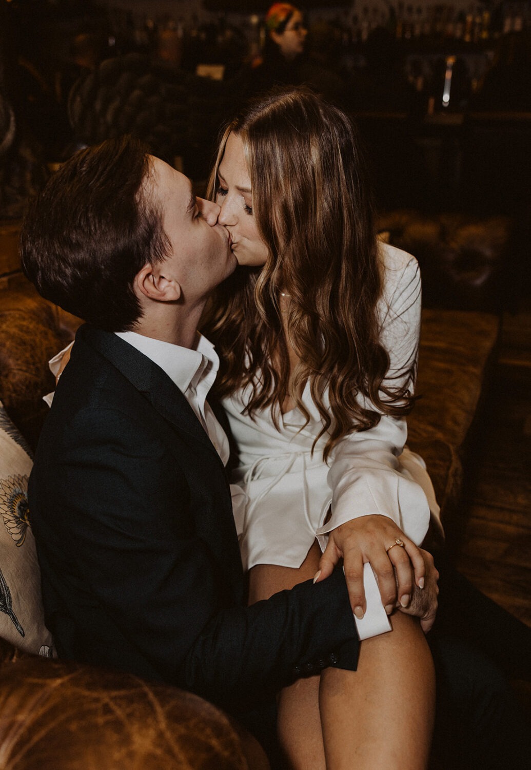 couple kisses on couch at bar engagement session 