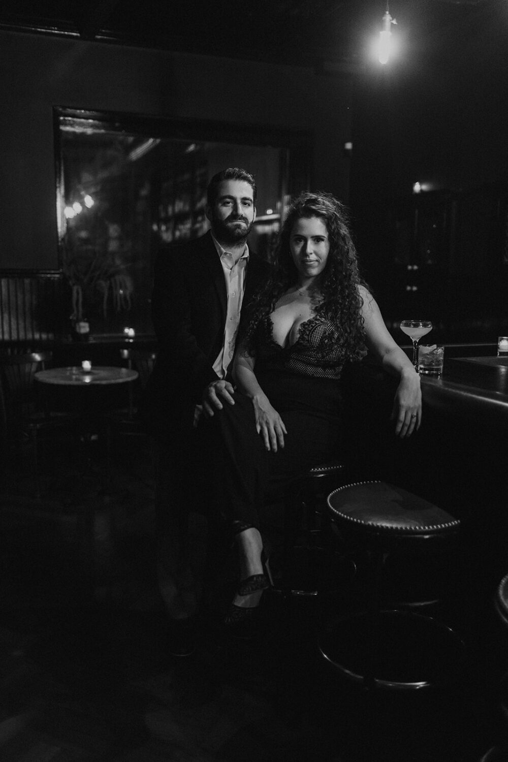 couple sits together at bar engagement session 