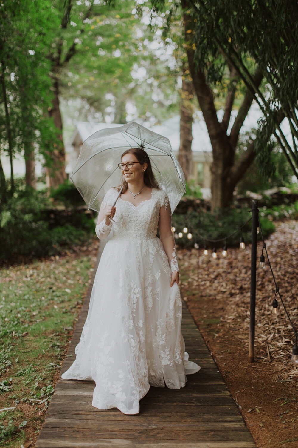 bride holds umbrella at rainy wedding venue