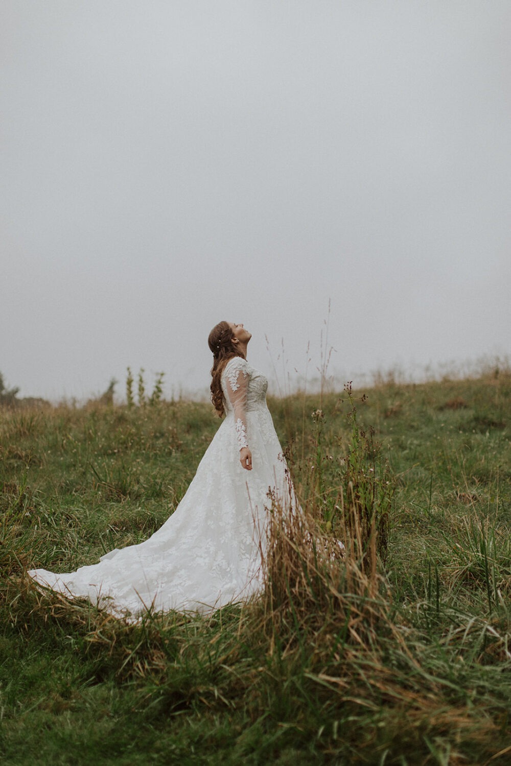 bride stands in rainy field during bridal portraits