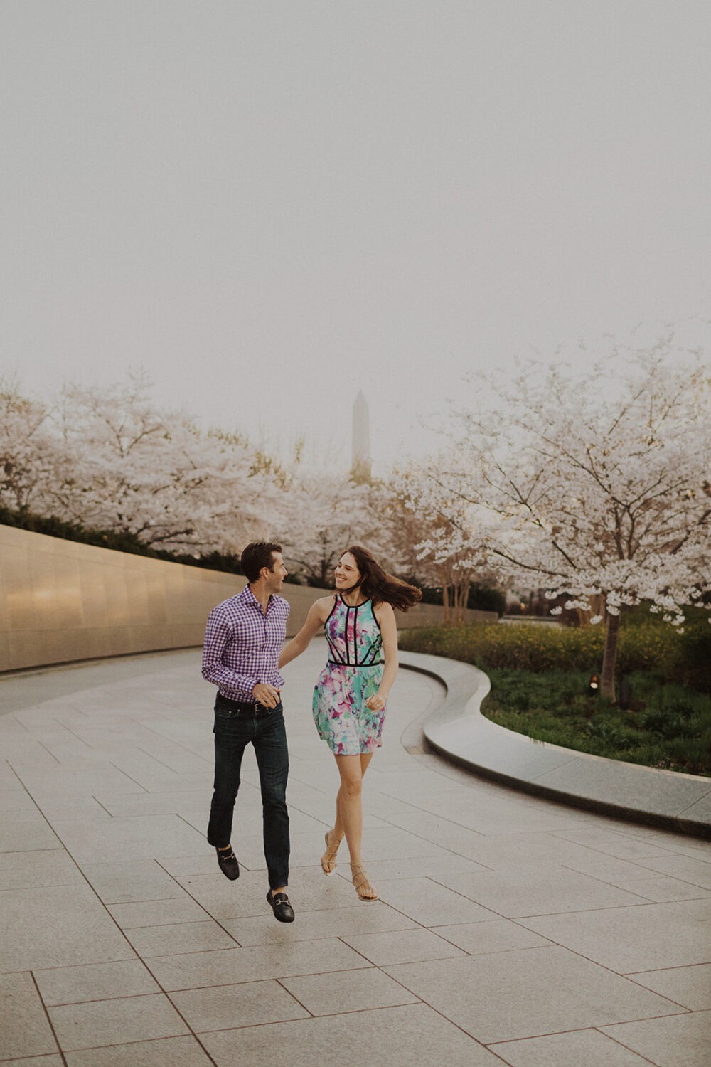 couple runs along cherry blossoms at sunrise DC engagement session 