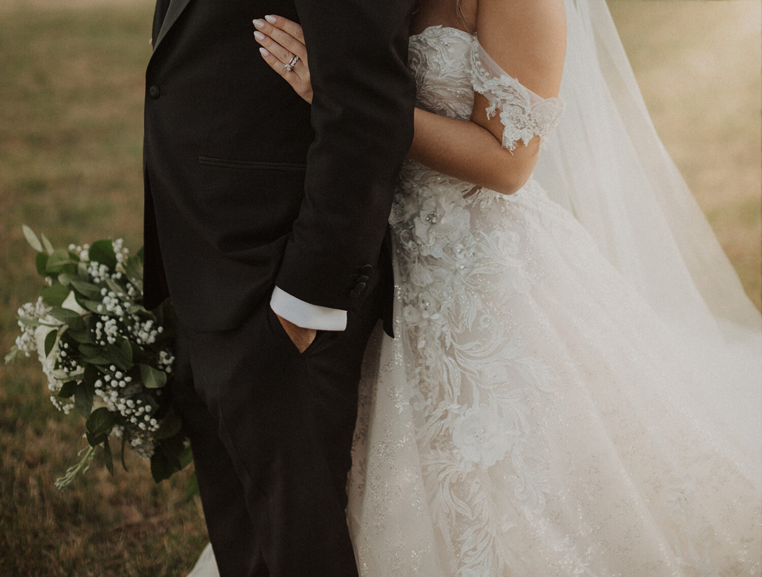 bride holds groom from behind at outdoor field wedding