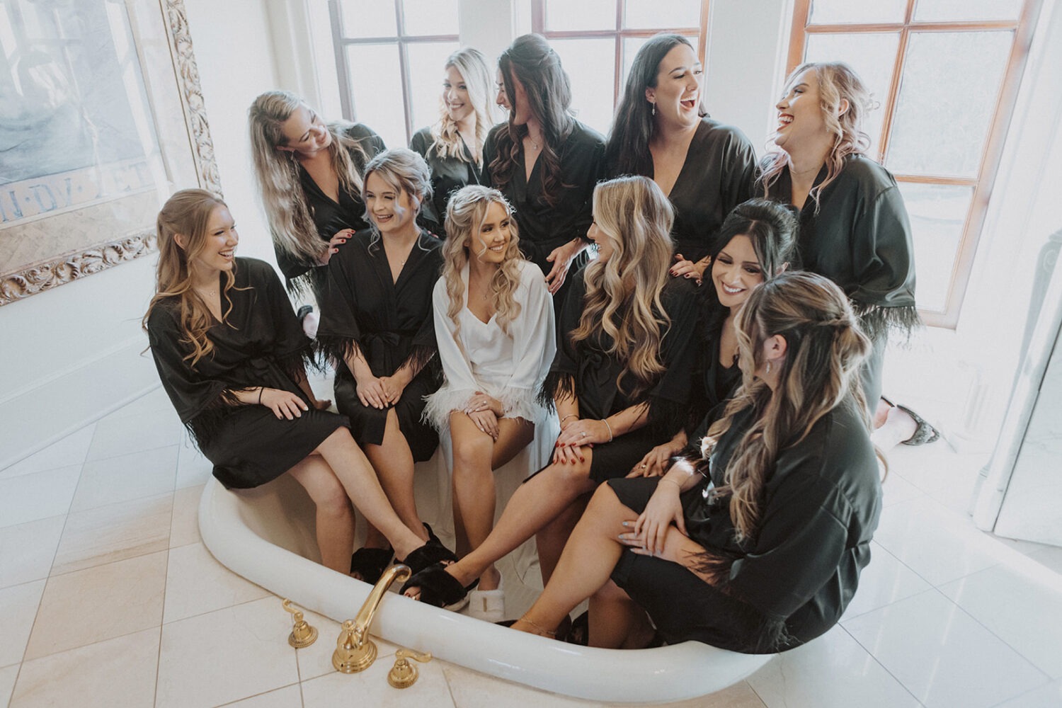bride sits with bridesmaids in wedding venue tub