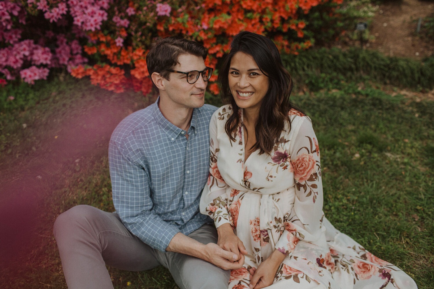 couple sits under flowers at National Arboretum spring engagement photos