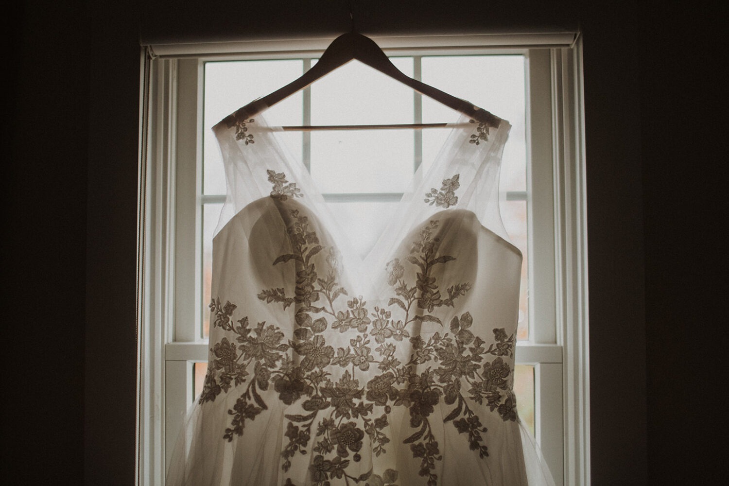 wedding dress hangs on window 