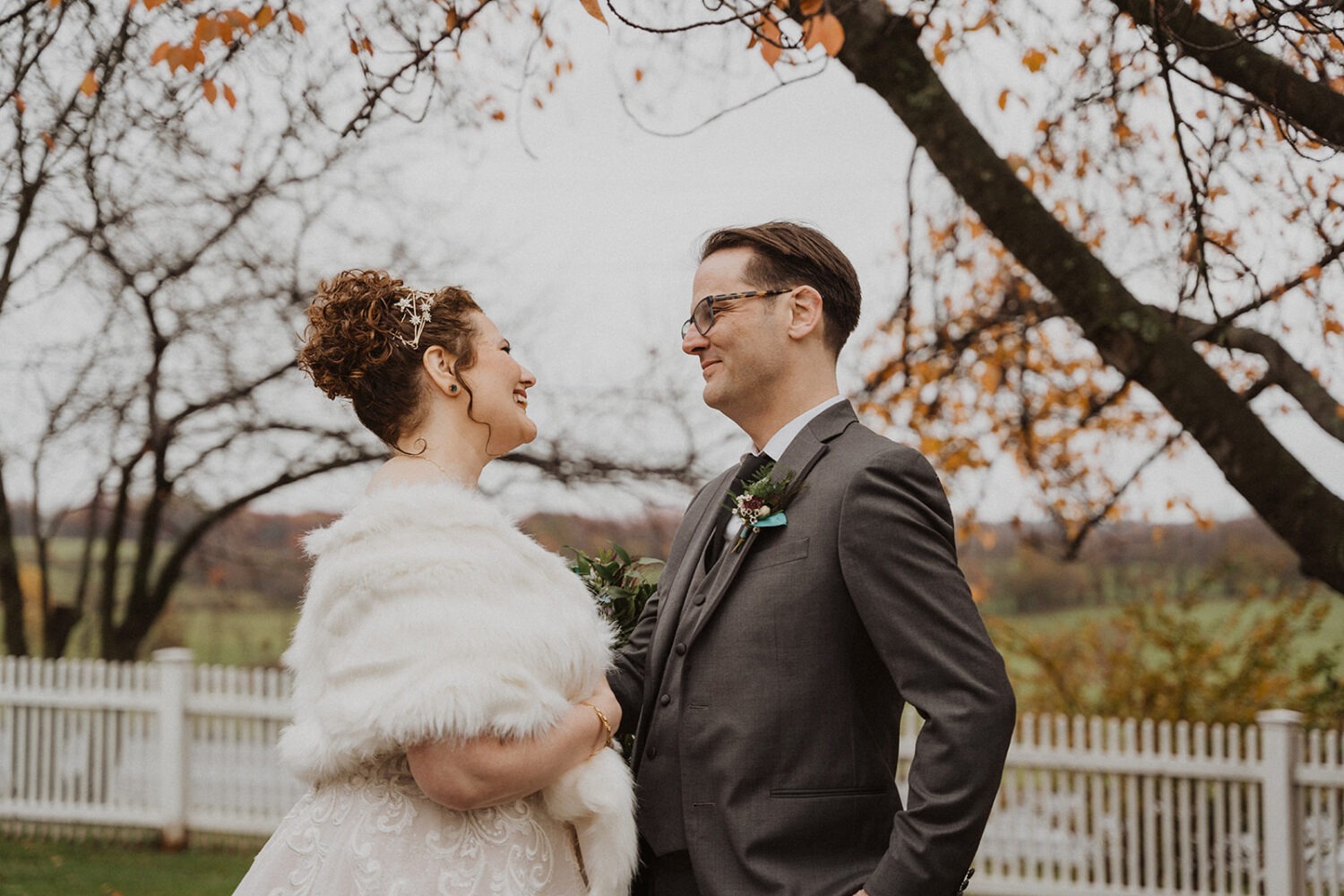 couple embraces under fall leaves on wedding day 