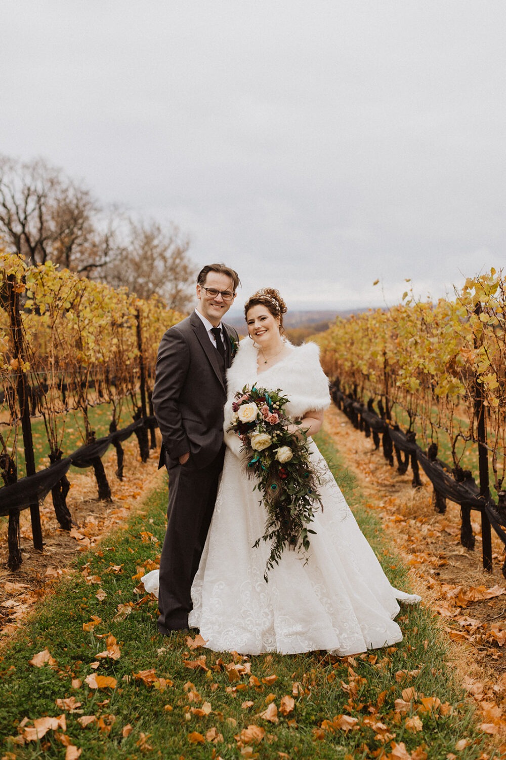 couple poses together in fall vineyard following wedding planning tips and advice
