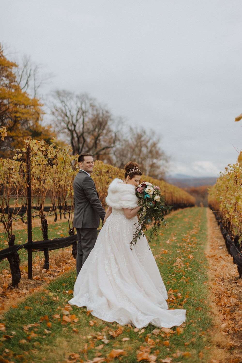 couple holds hands in vineyard at outdoor wedding
