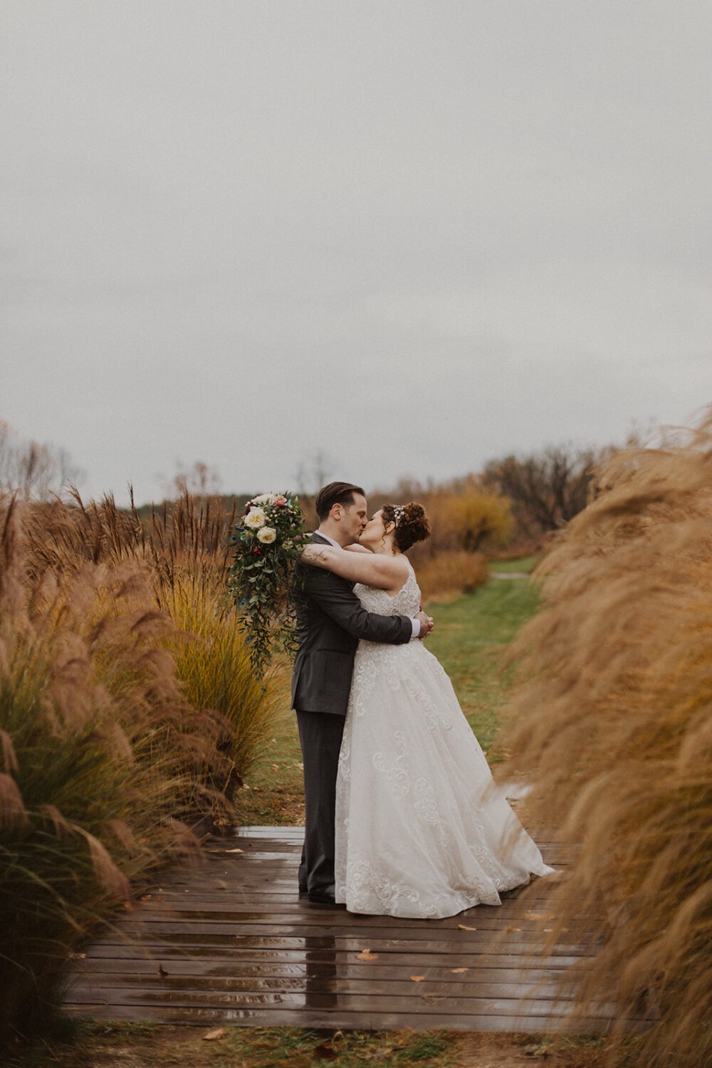 couple kisses at outdoor wedding in rain 