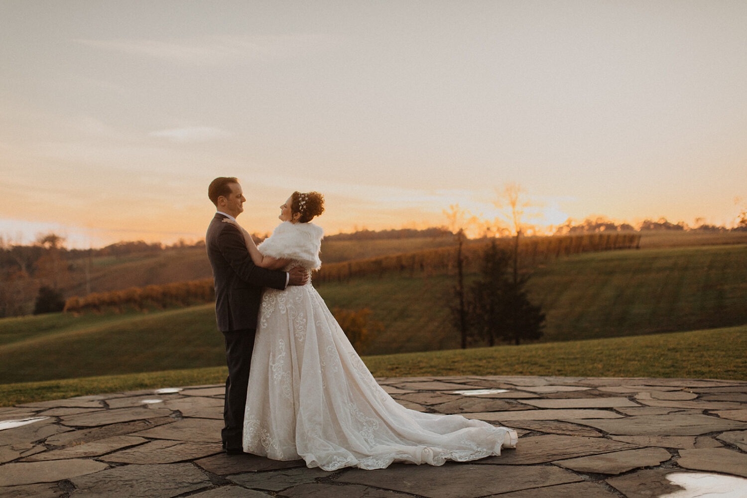 couple stands on patio together at sunset 