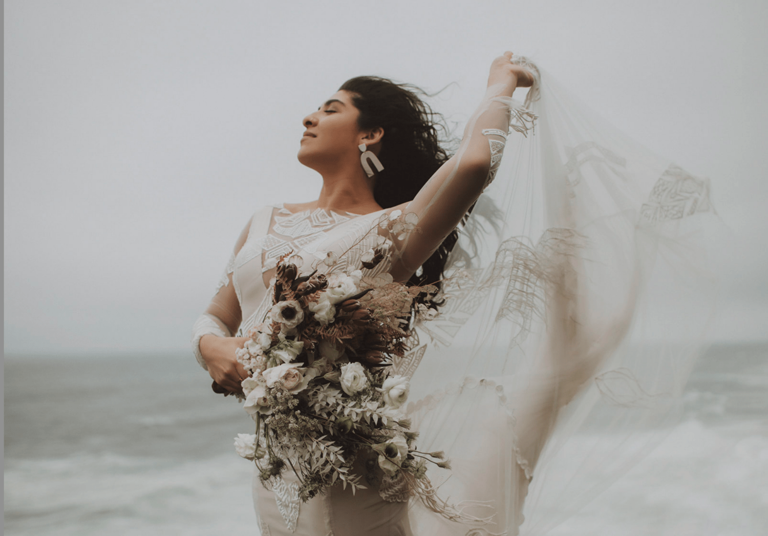 bride holds wedding dress train at windy elopement
