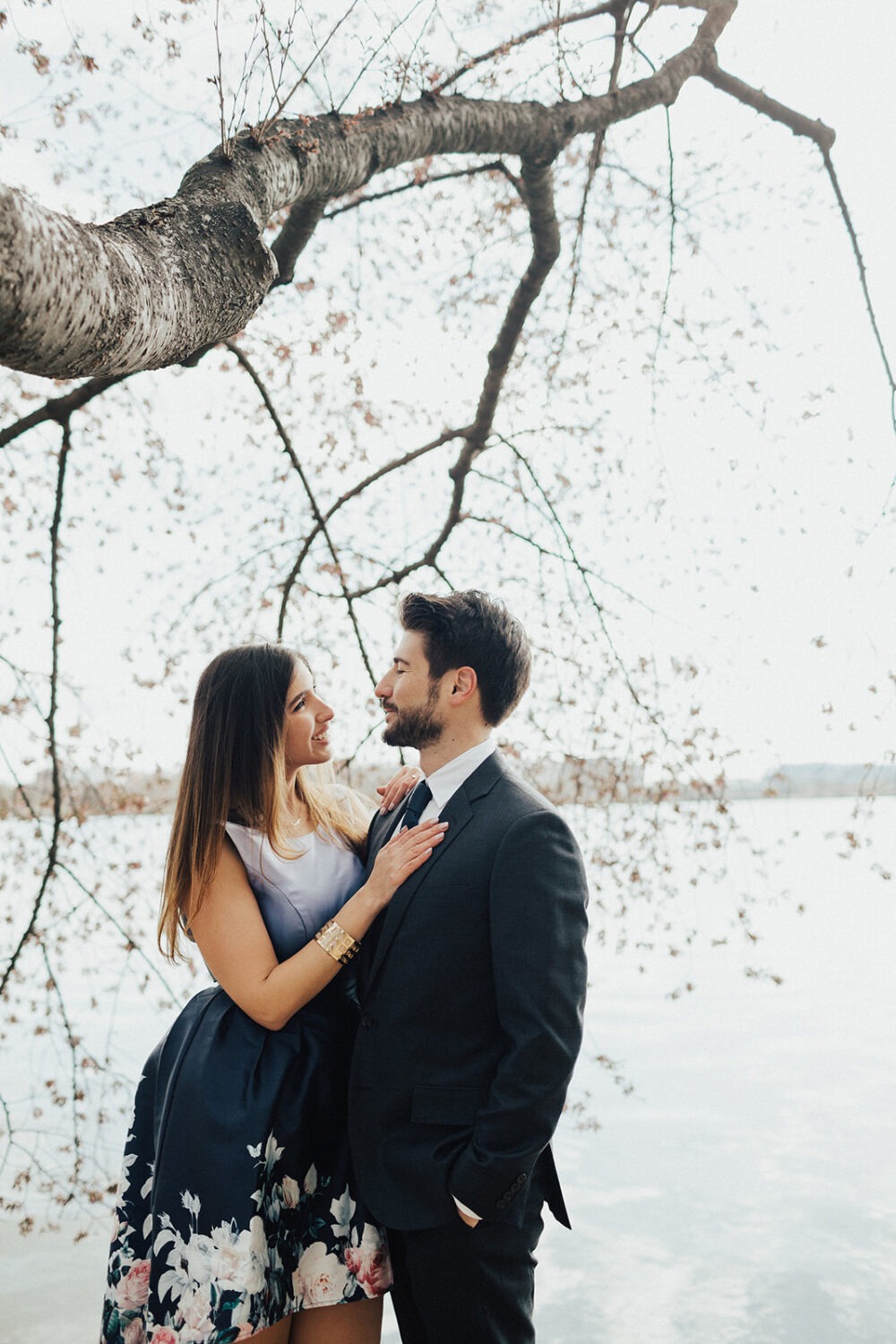 couple embraces under cherry blossoms for DC spring engagement photos