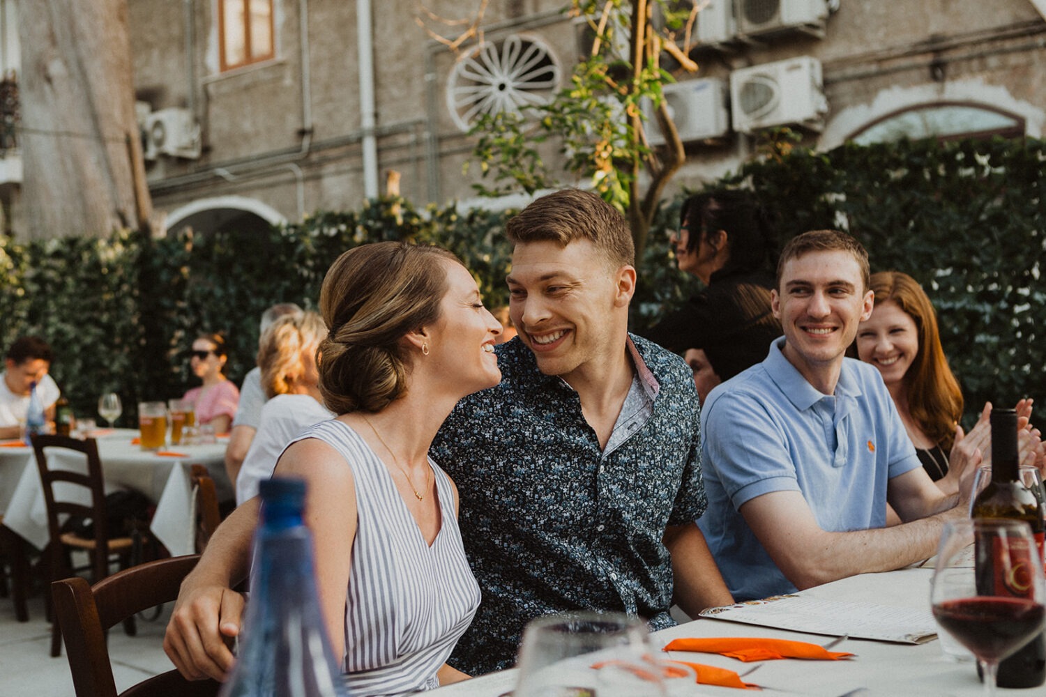 couple laughs with guests at wedding rehearsal dinner