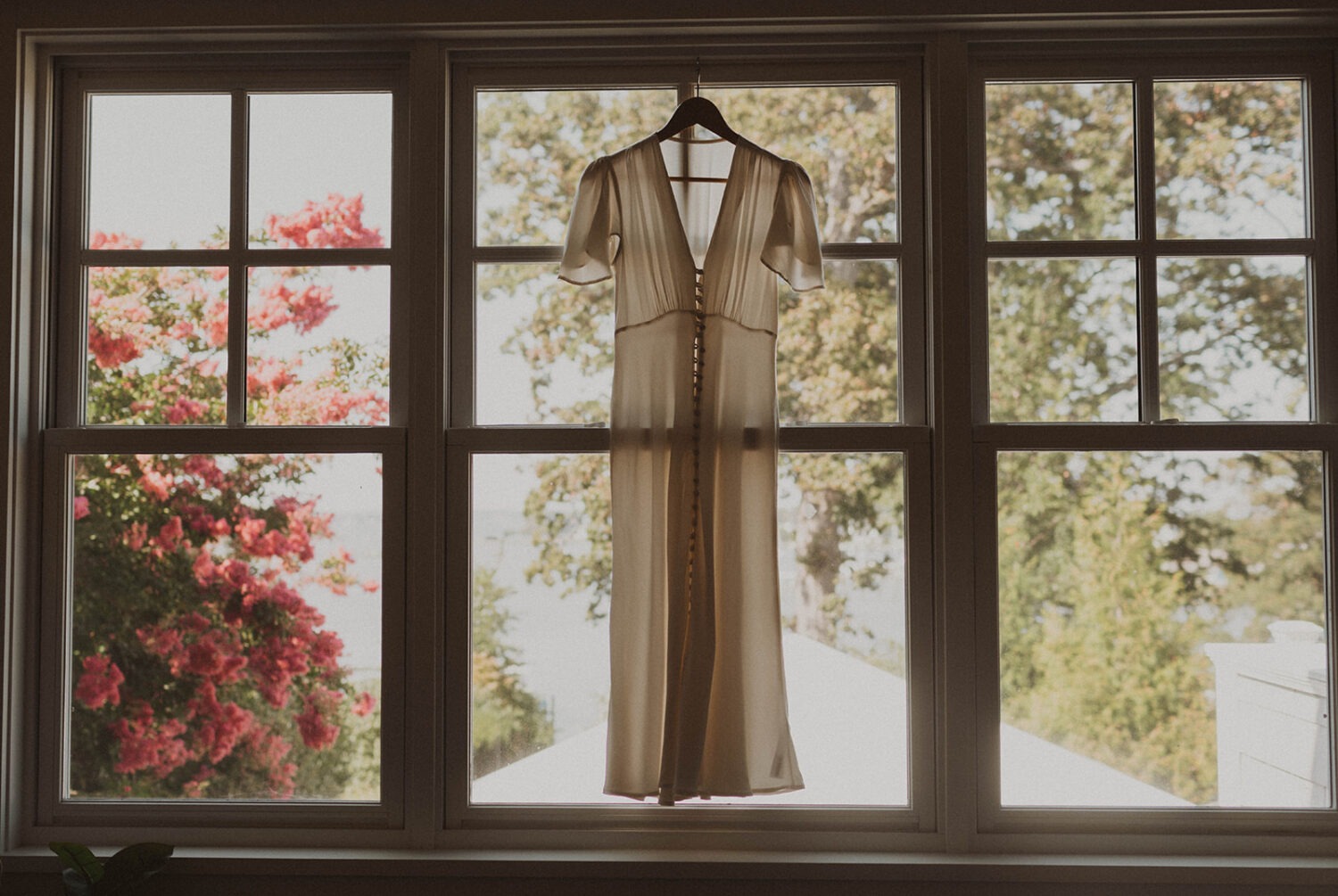 wedding dress hangs in window 