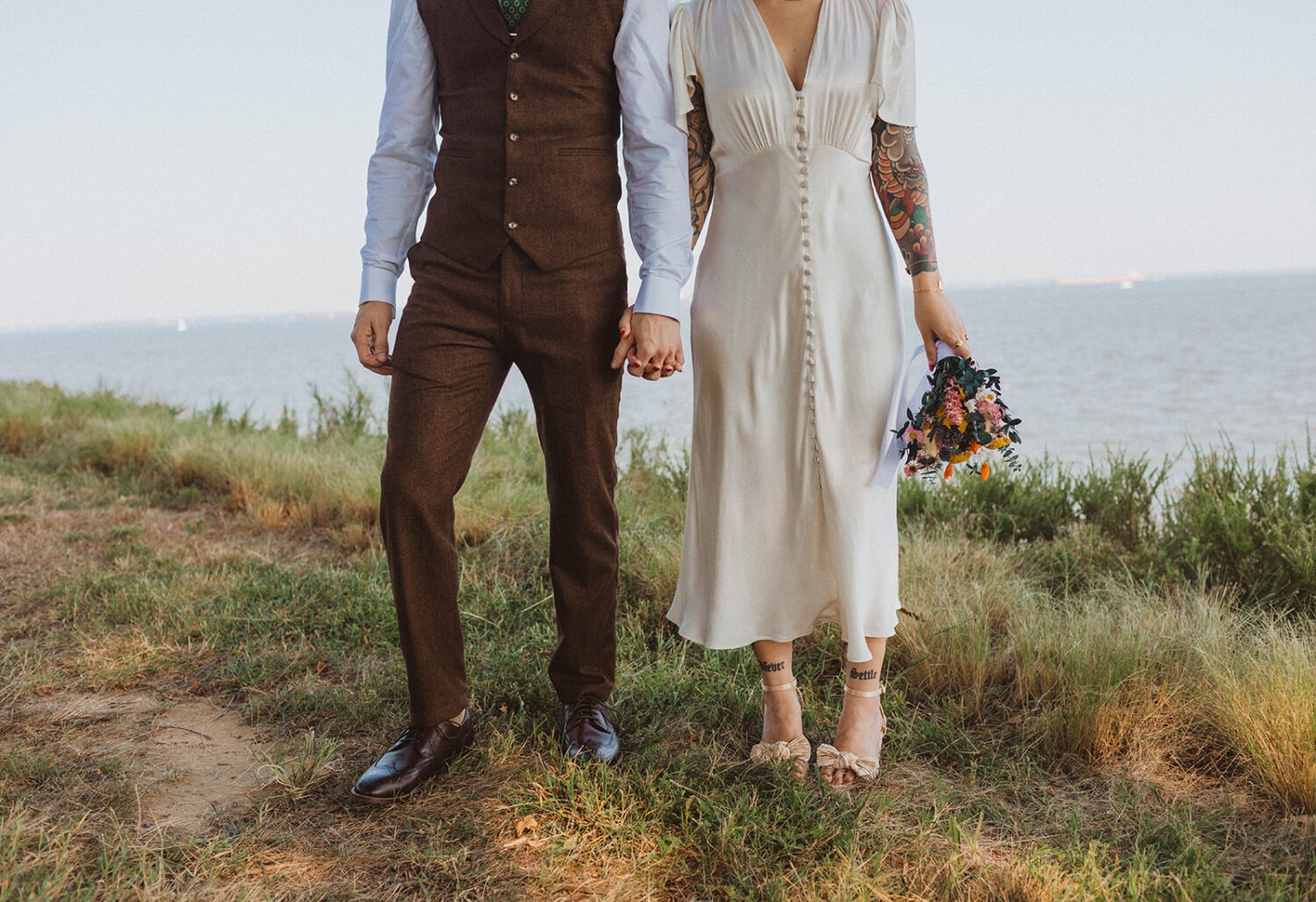 couple holds hands together at waterfront wedding venue