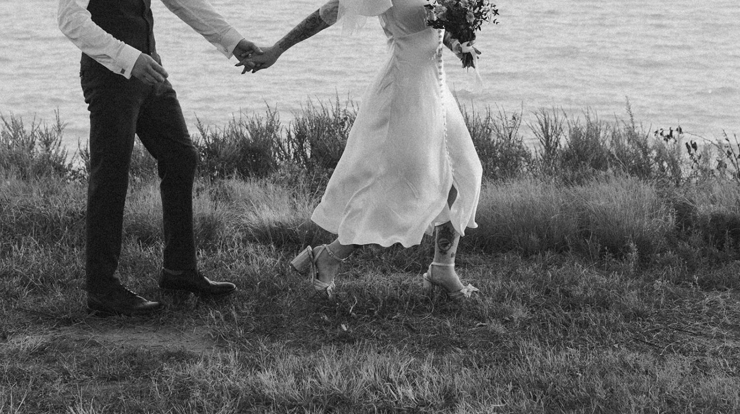 couple runs holding hands at waterfront wedding