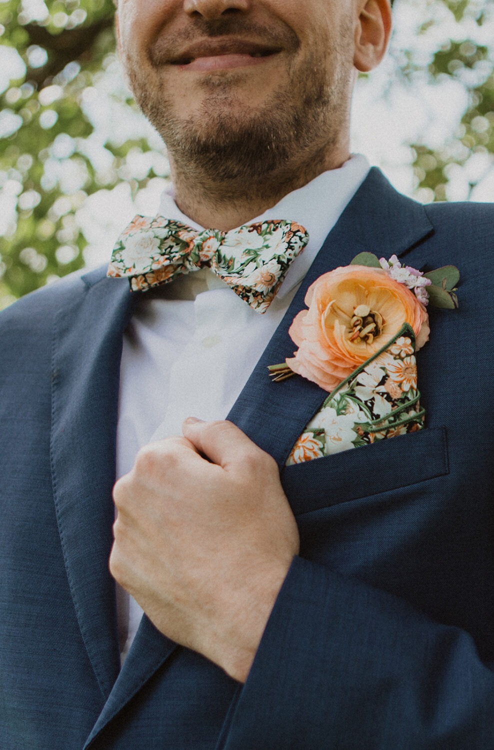 groom holds jacket with flower and wedding bow tie