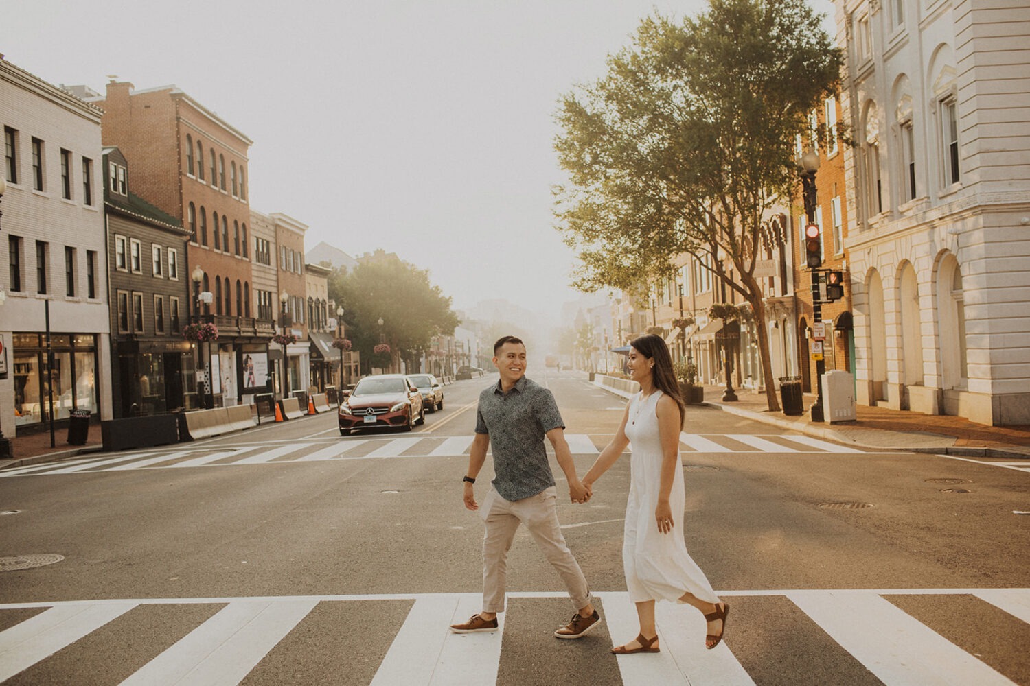 couple crosses street holding hands at sunrise Georgetown engagement session 