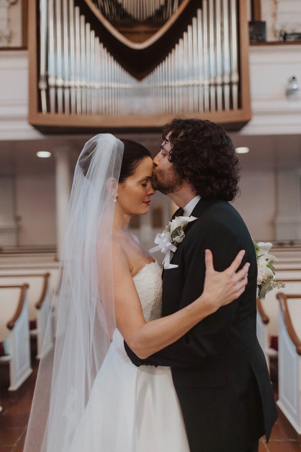 couple kisses at historic church wedding with organ