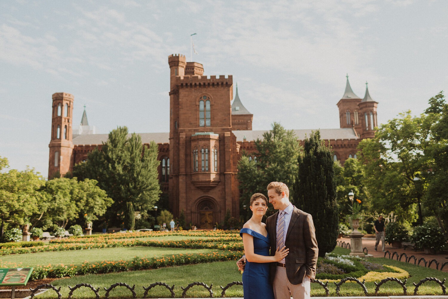 couple stands in front of Smithsonian castle garden