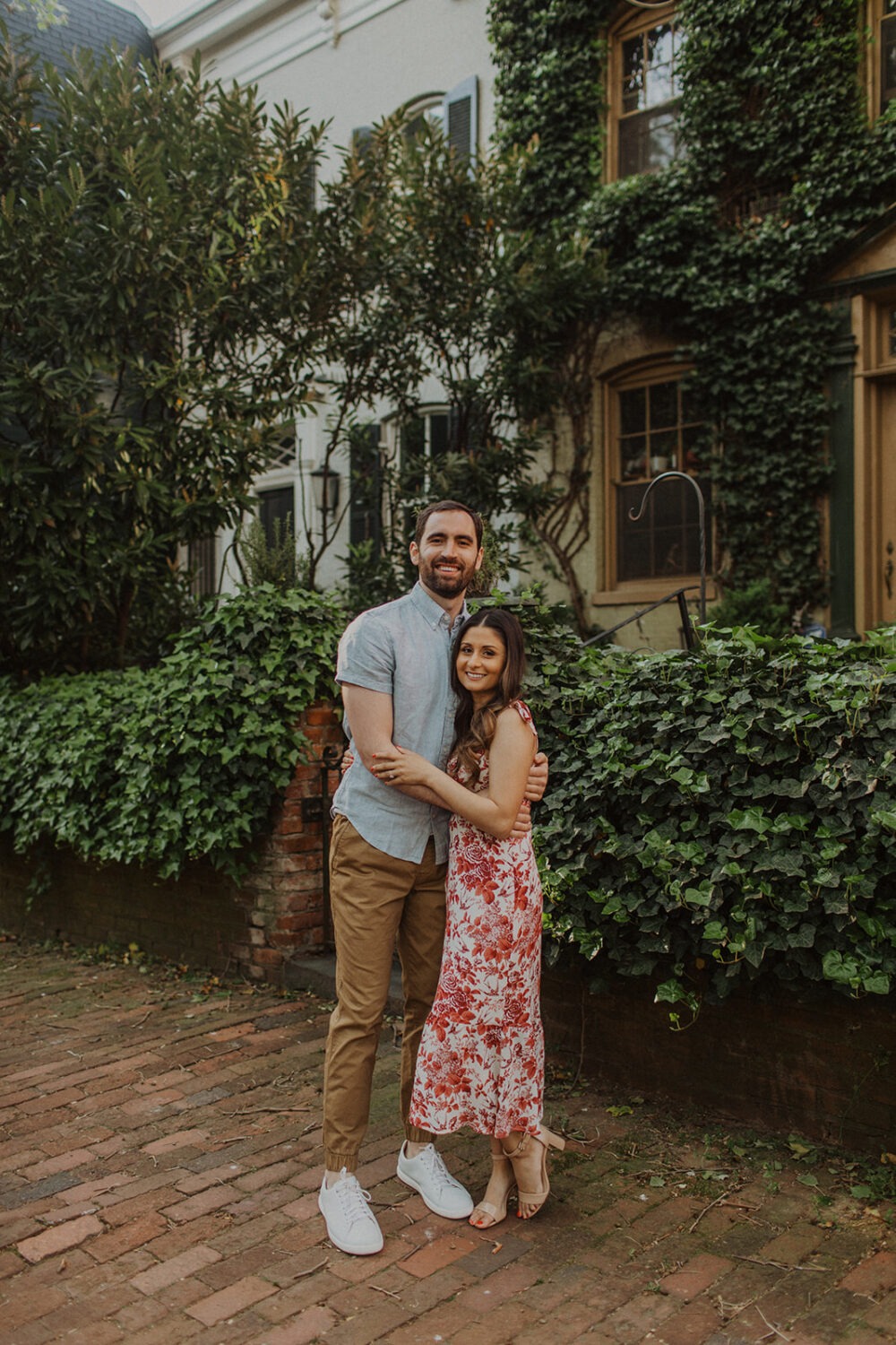couple embraces in front of Georgetown ivy-covered row house 