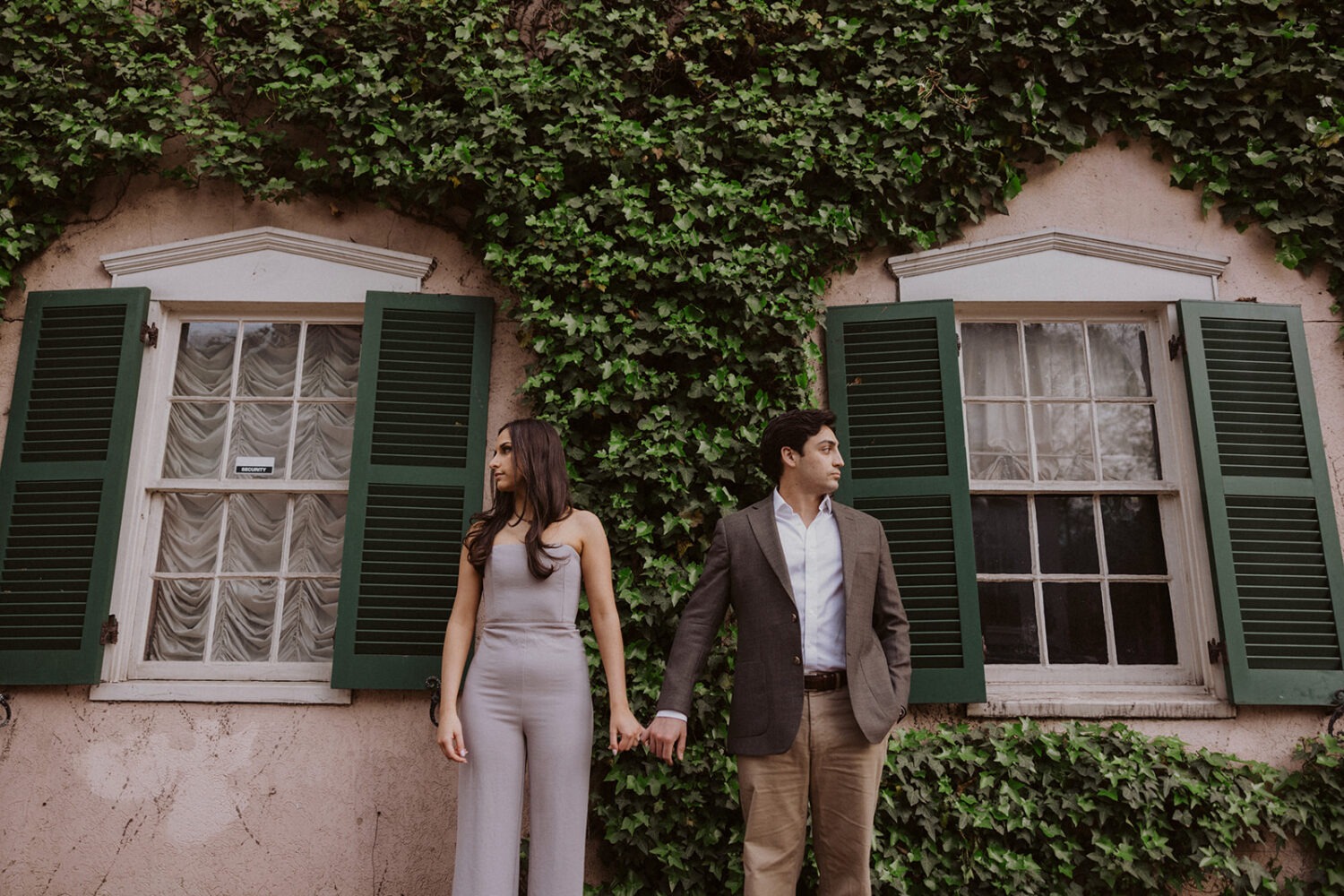 couple holds hands in front of Georgetown ivy-covered row house 