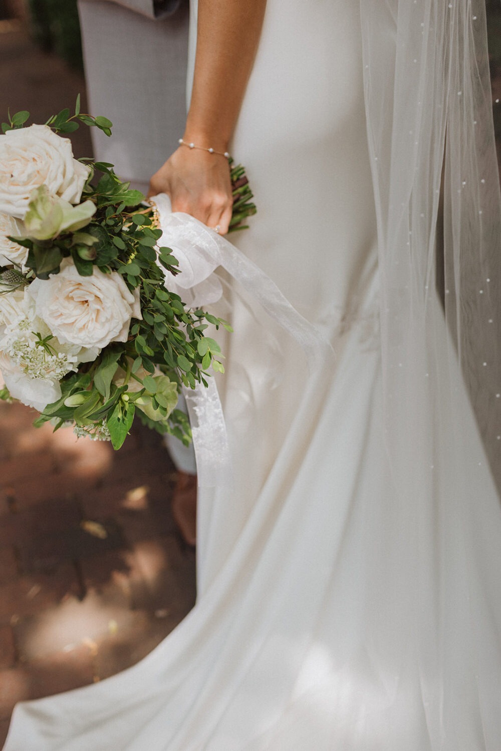 bride walks holding white rose wedding bouquet 