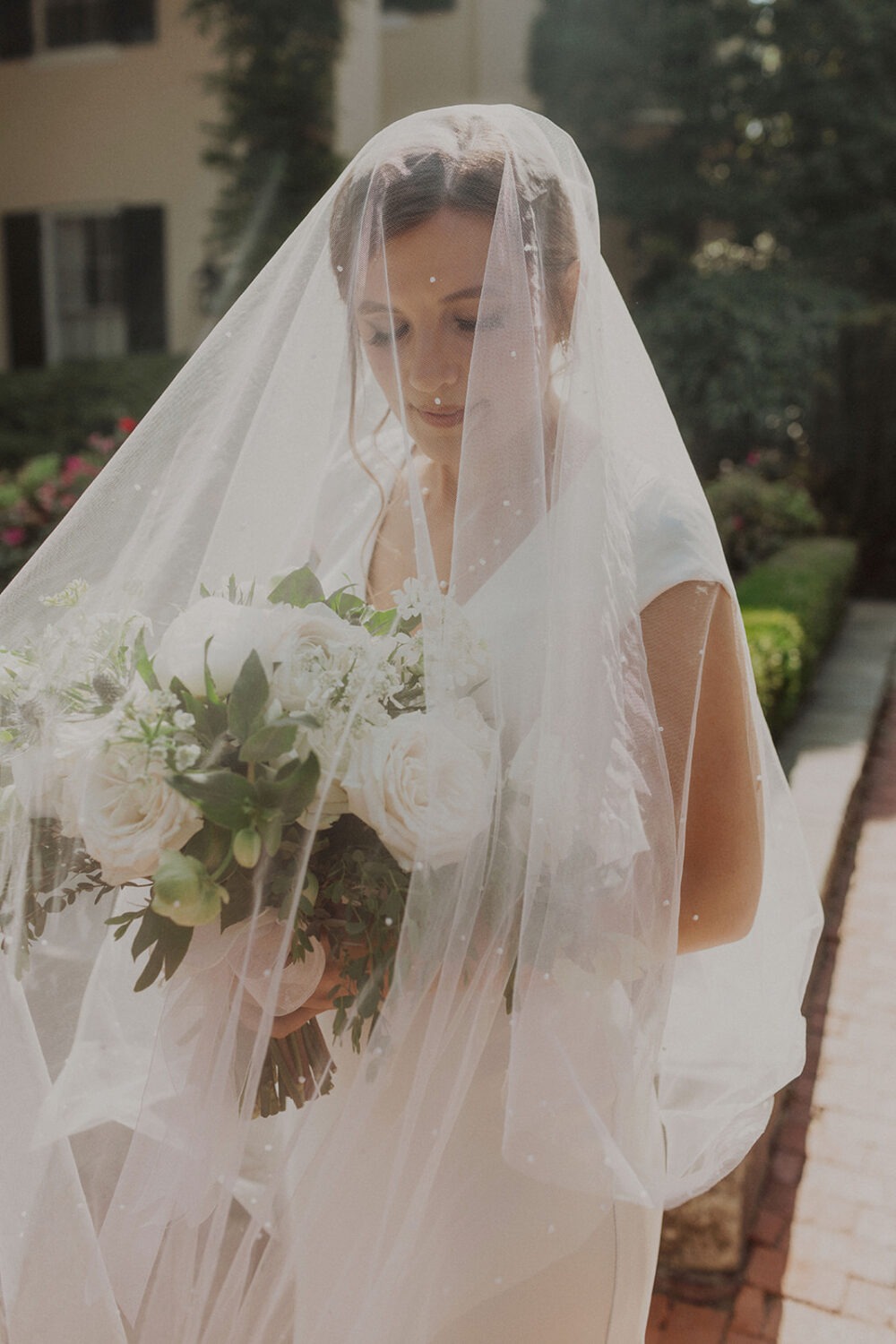 bride holds wedding bouquet under wedding veil