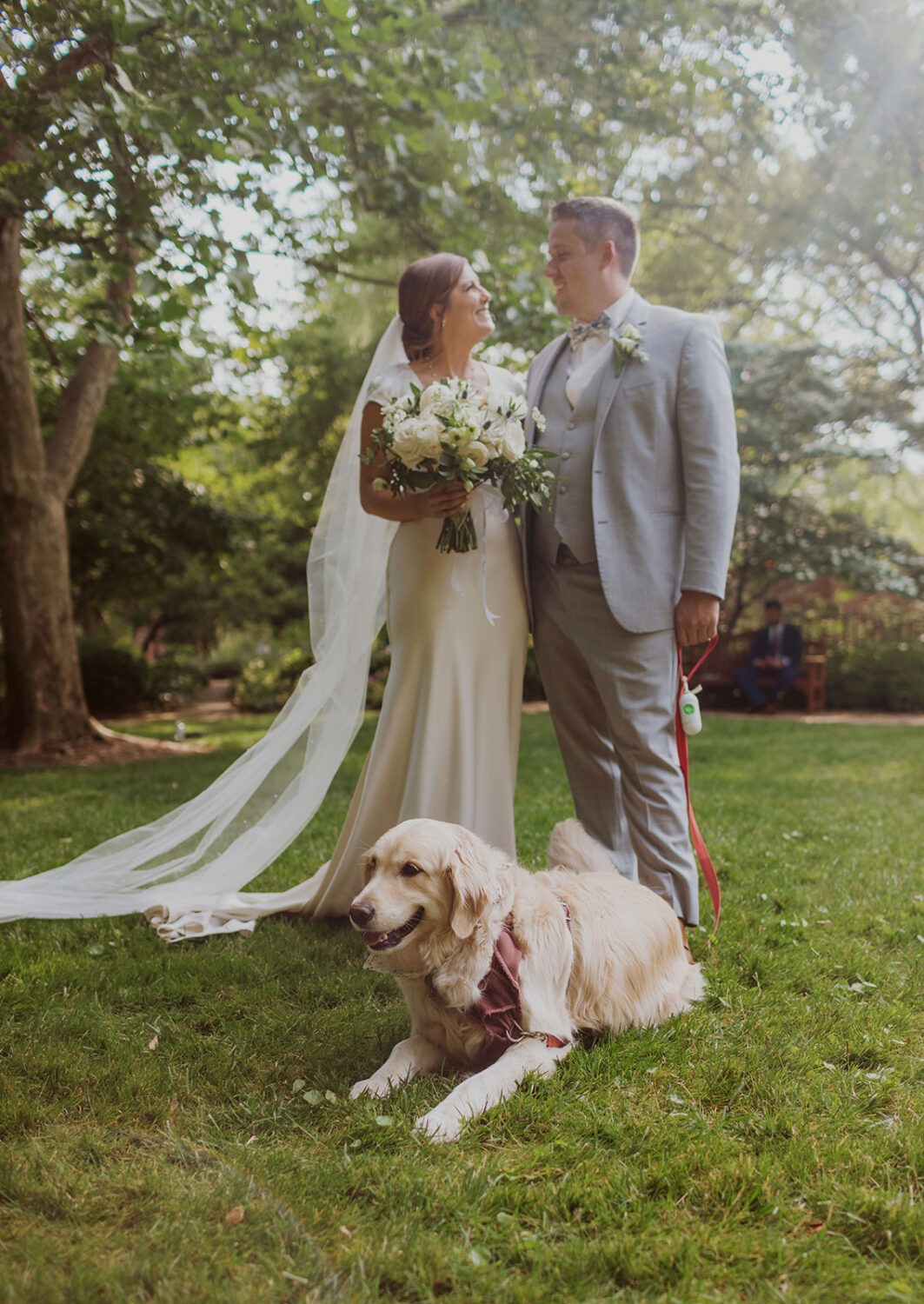 couple poses with dog at outdoor wedding 