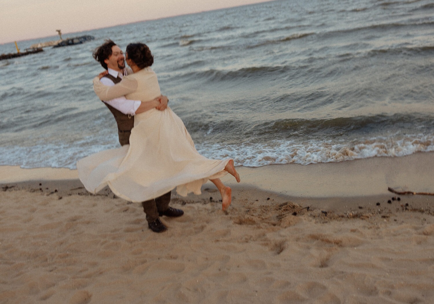 couple twirls at beach engagement session